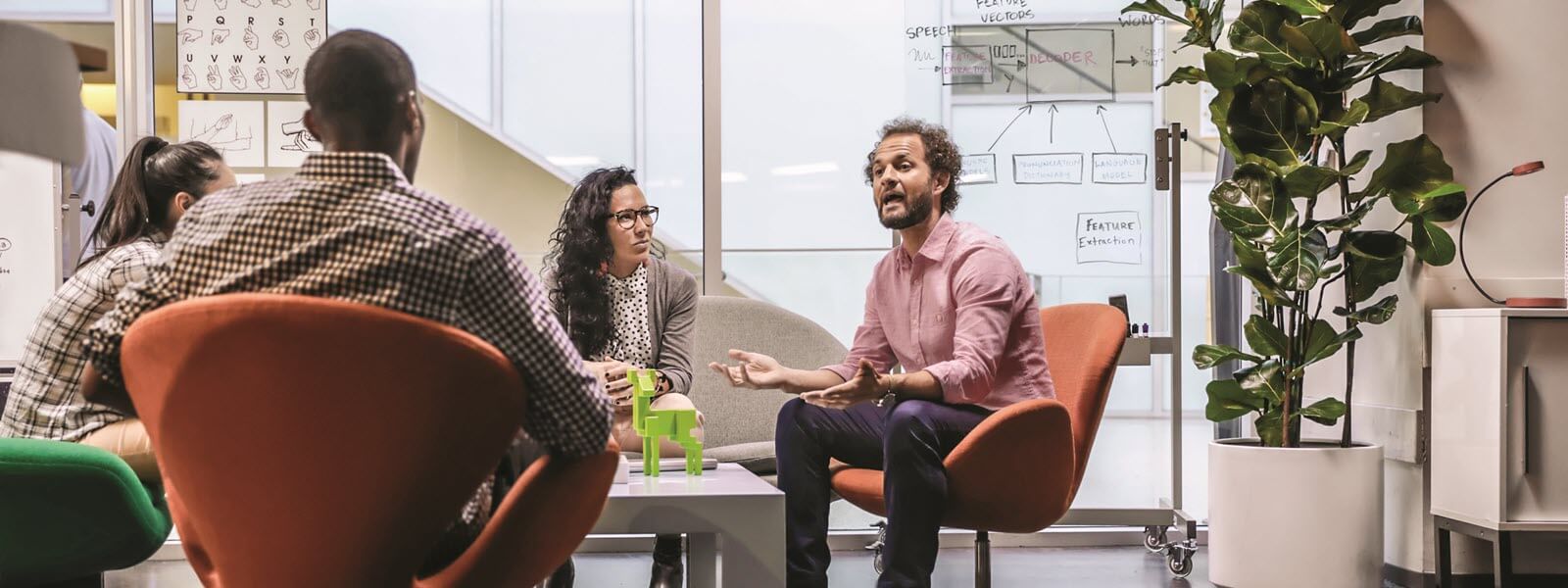 Team members sit around conference table having a discussion.