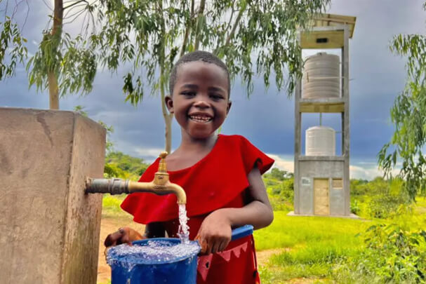 Young child getting water at solar water system