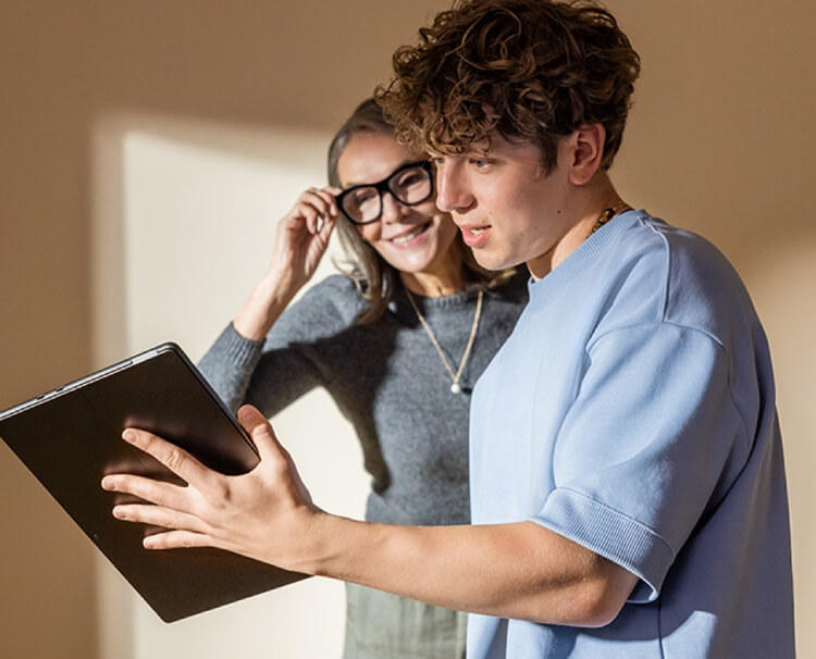 Two people talking and looking at a tablet device.