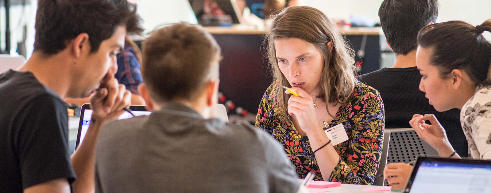 A woman is deep in thought while in consultation with three other people